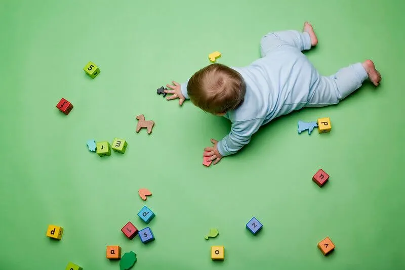 A newborn baby crawling between scattered letter blocks