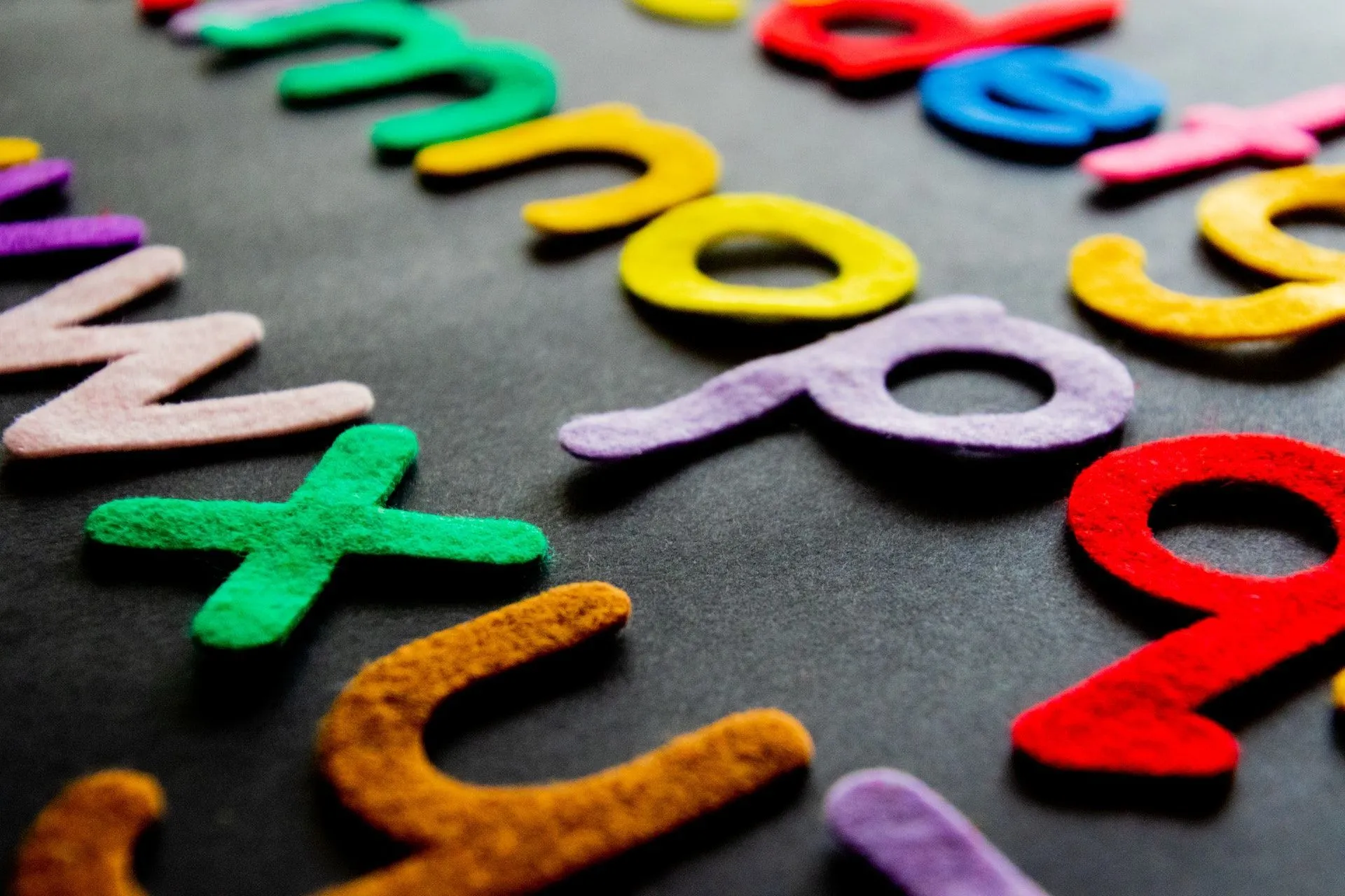 Colourful fabric alphabet arranged on a black background