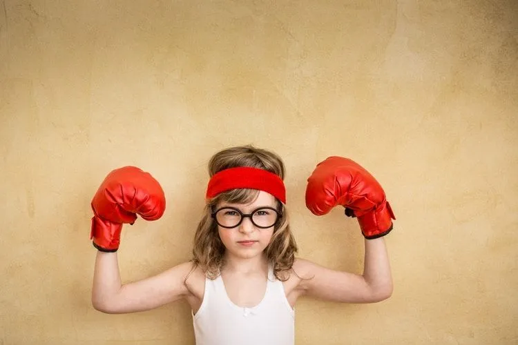 A little girl posing with boxing gloves