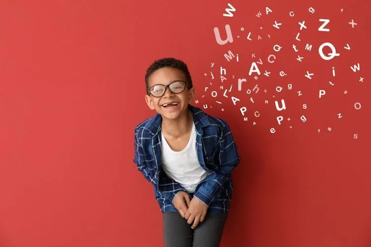 A boy smiling and letters scattered on red background