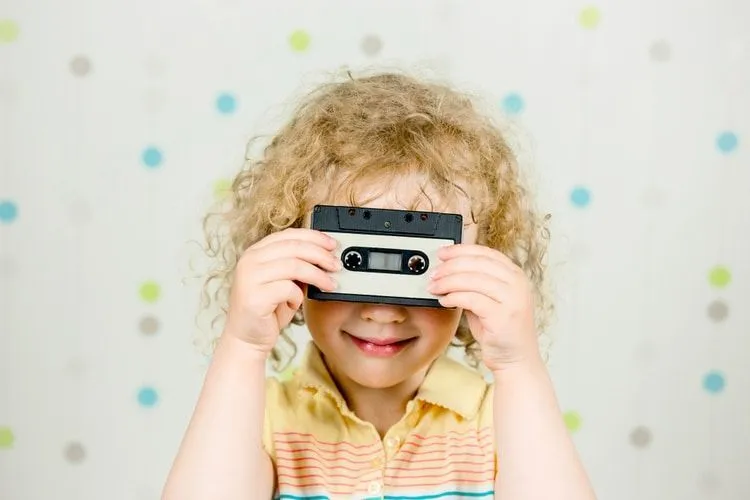 A girl holding and looking through retro 80s cassette tape indoors