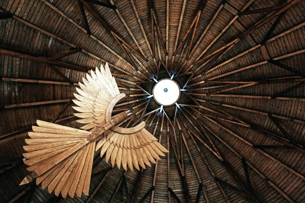 A carved wooden phoenix hanging by the circular ceiling