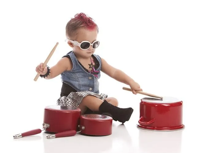 Adorable toddler with a pink mohawk and banging on pots and pans.