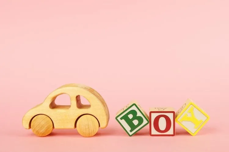 Colored cubes with letters Boy and car toy on a pink background