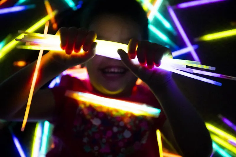 girl smiling as she hold glowsticks on her hands