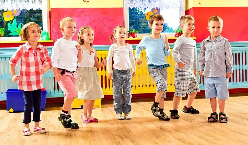 Group of children dancing together in a playroom in a nursery school.
