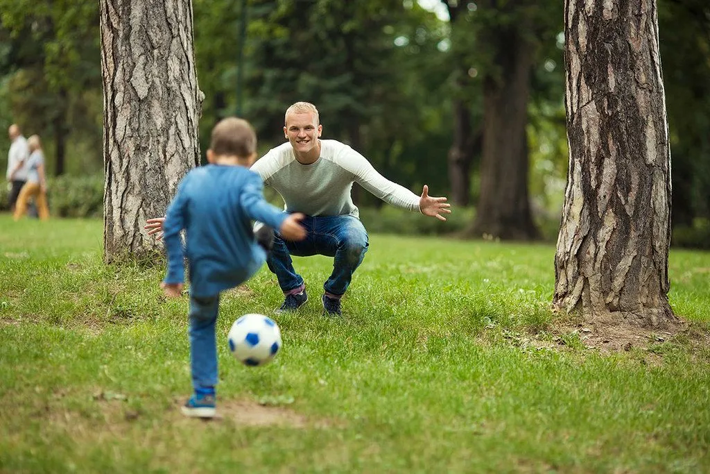 father and son playing football together