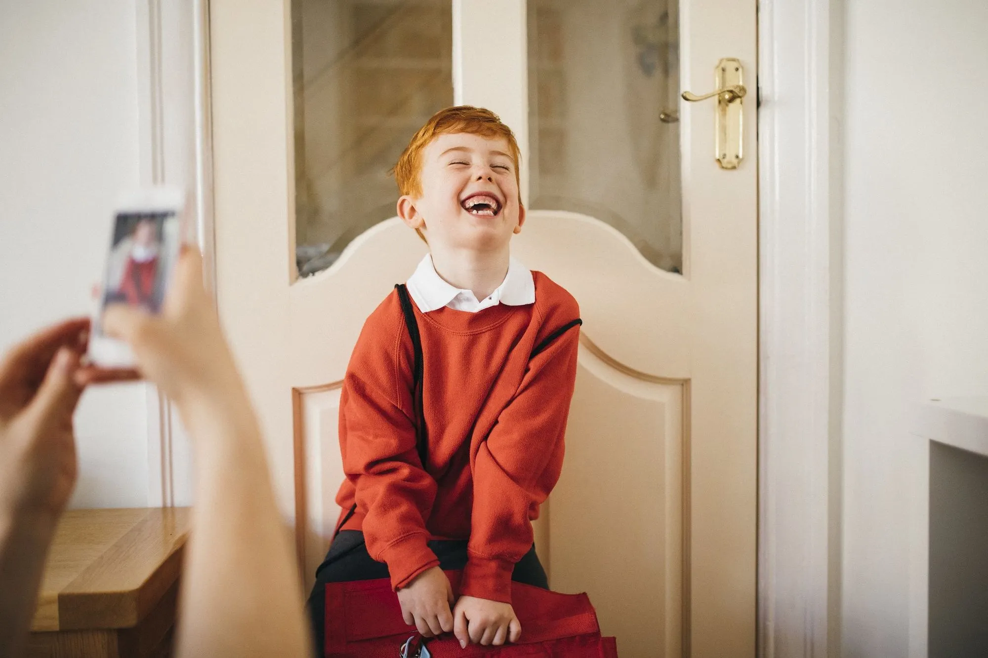 red-haired boy in school uniform posing in front of door