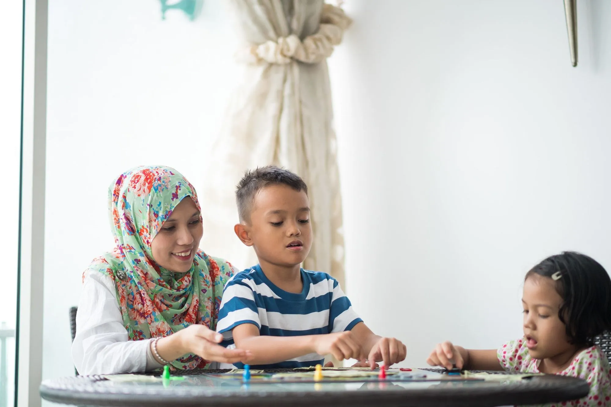 2 children playing board game with their mother