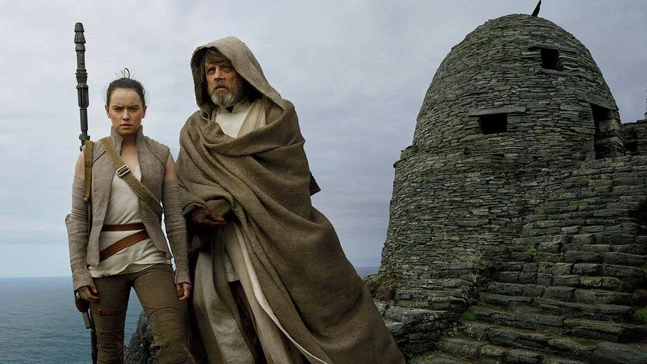 Rey and Luke Skywalker stand together on a clifftop
