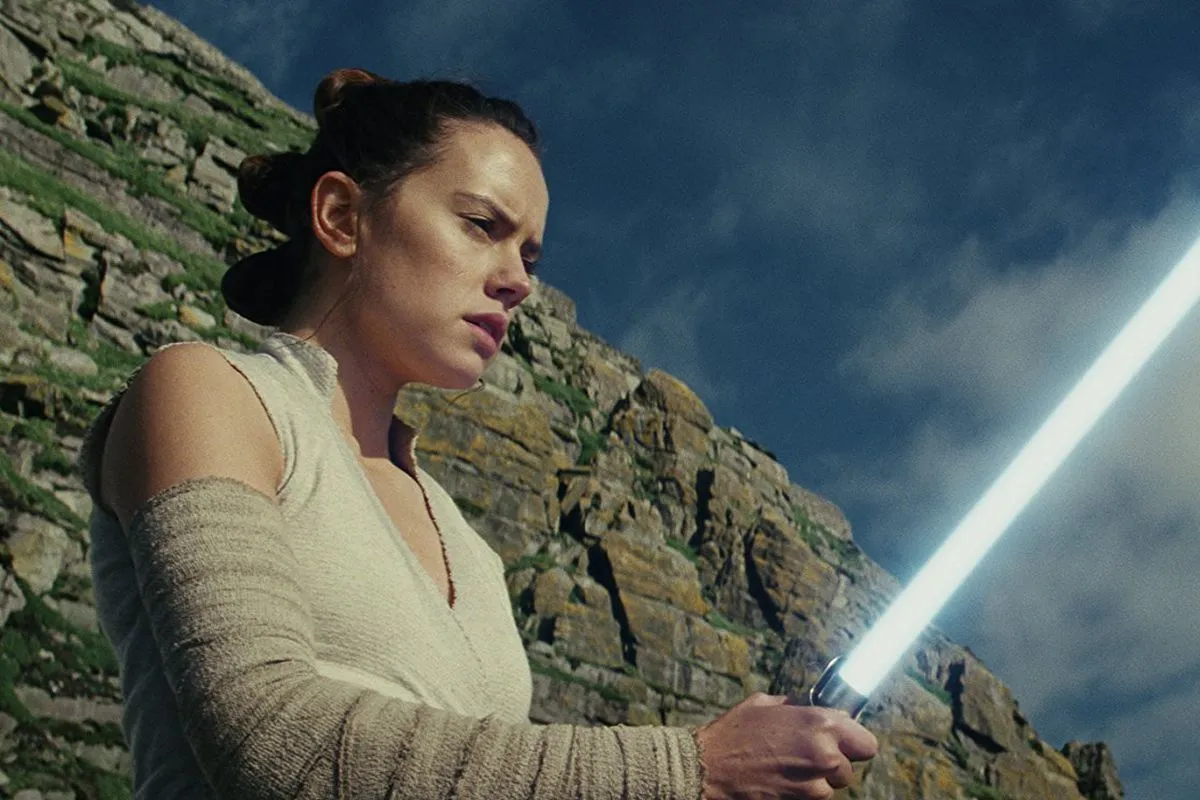 Rey stood with lightsaber on clifftop