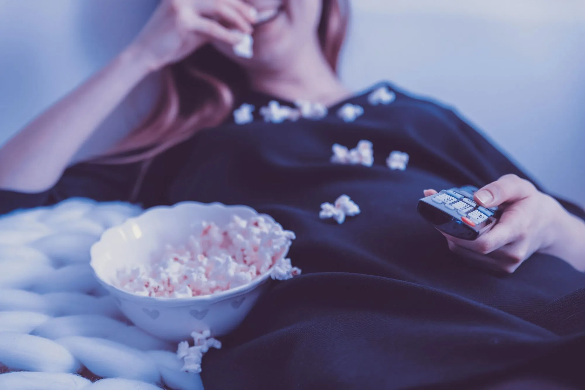 young woman eating popcorn watching a film
