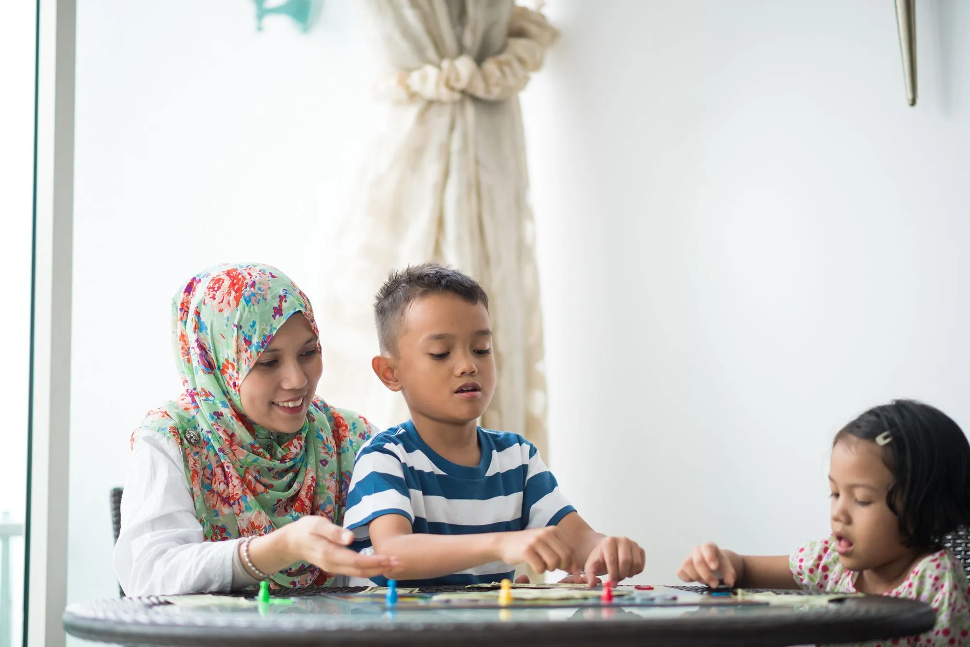 mother playing board game with son and daughter