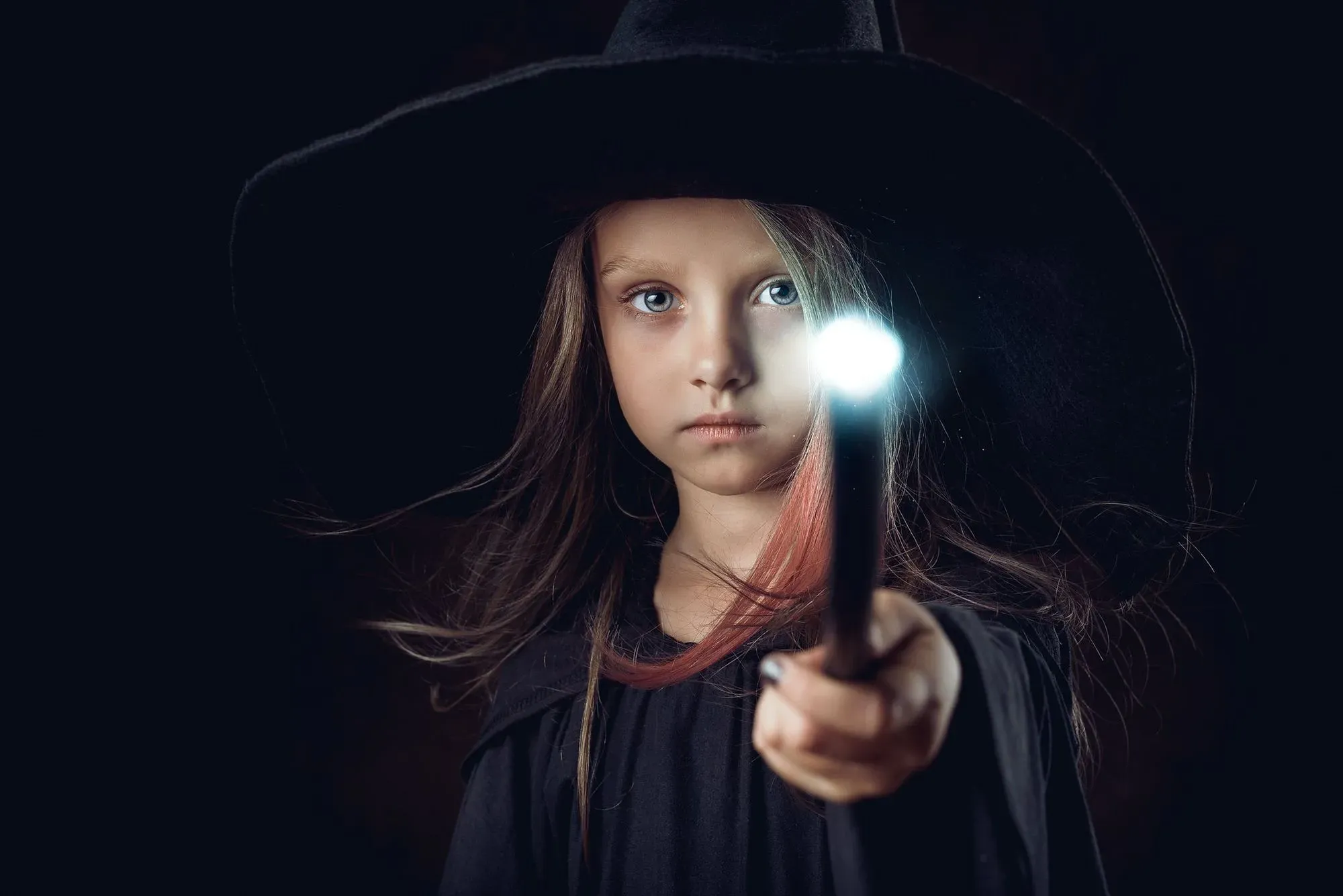 girl dressed as a witch holding a wand