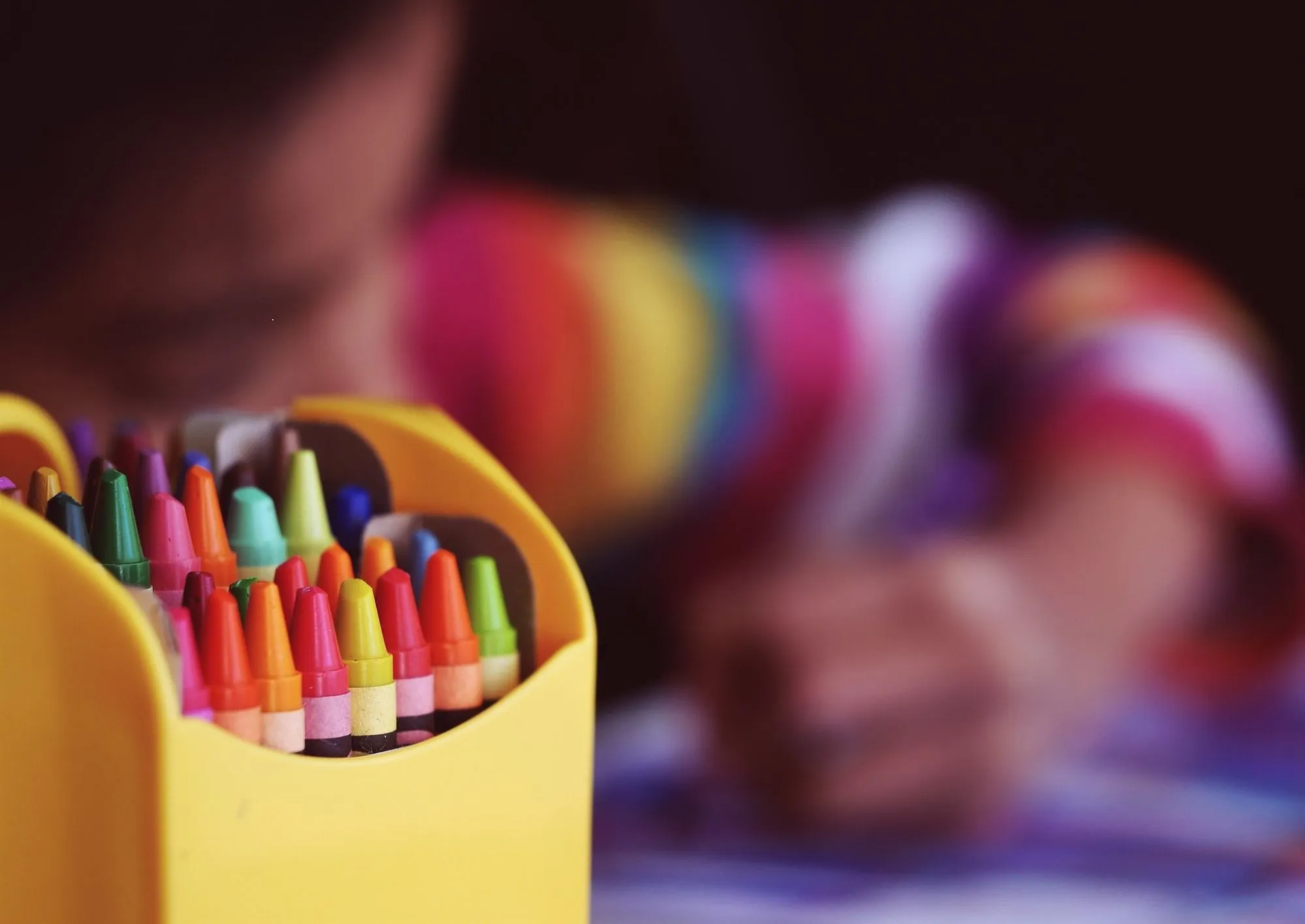 child using crayons to colour