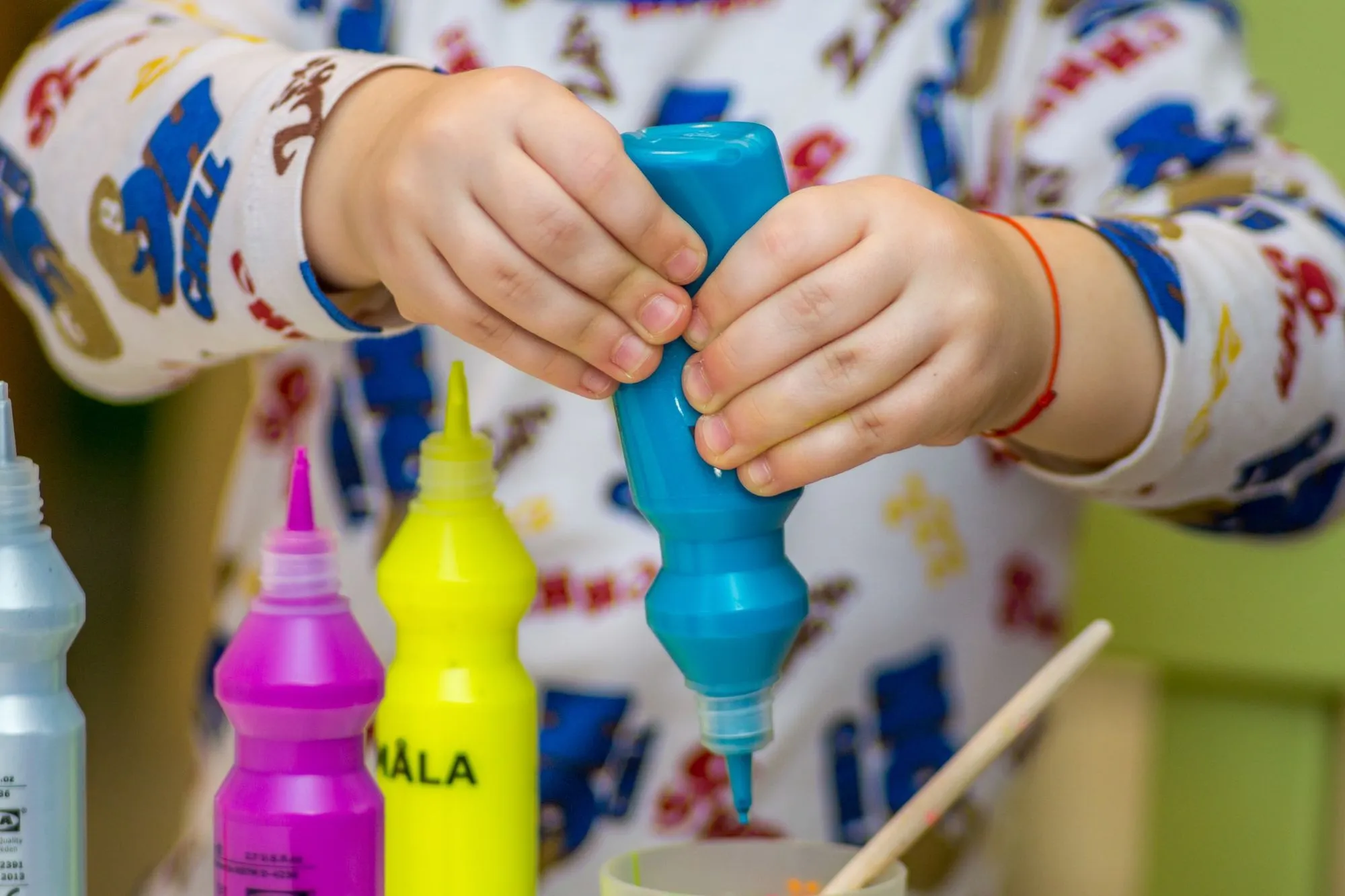 child squeezing paint bottle
