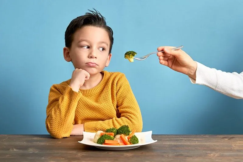 A child struggling to try new foods.