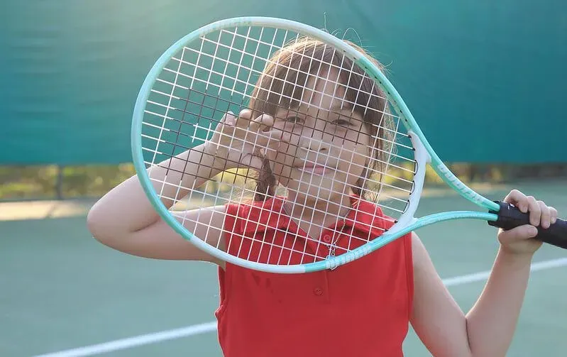 Child hiding behind racket.