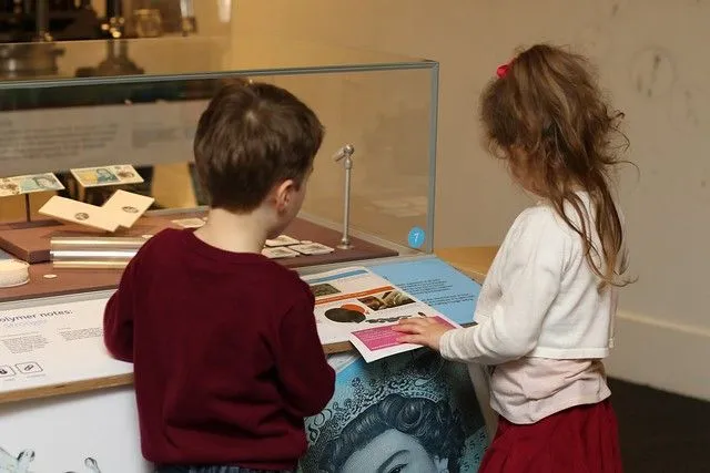a little girl and boy at the bank of england museum looking at an exhibit 