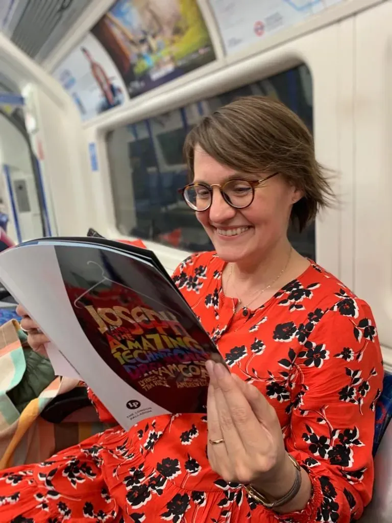 A woman reading the show programme from Joseph the Musical on the tube