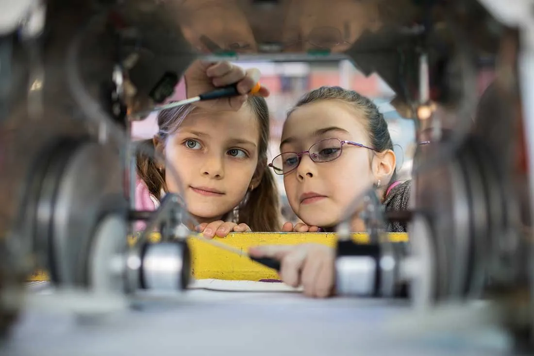 Two future engineers looking at a mechanism.