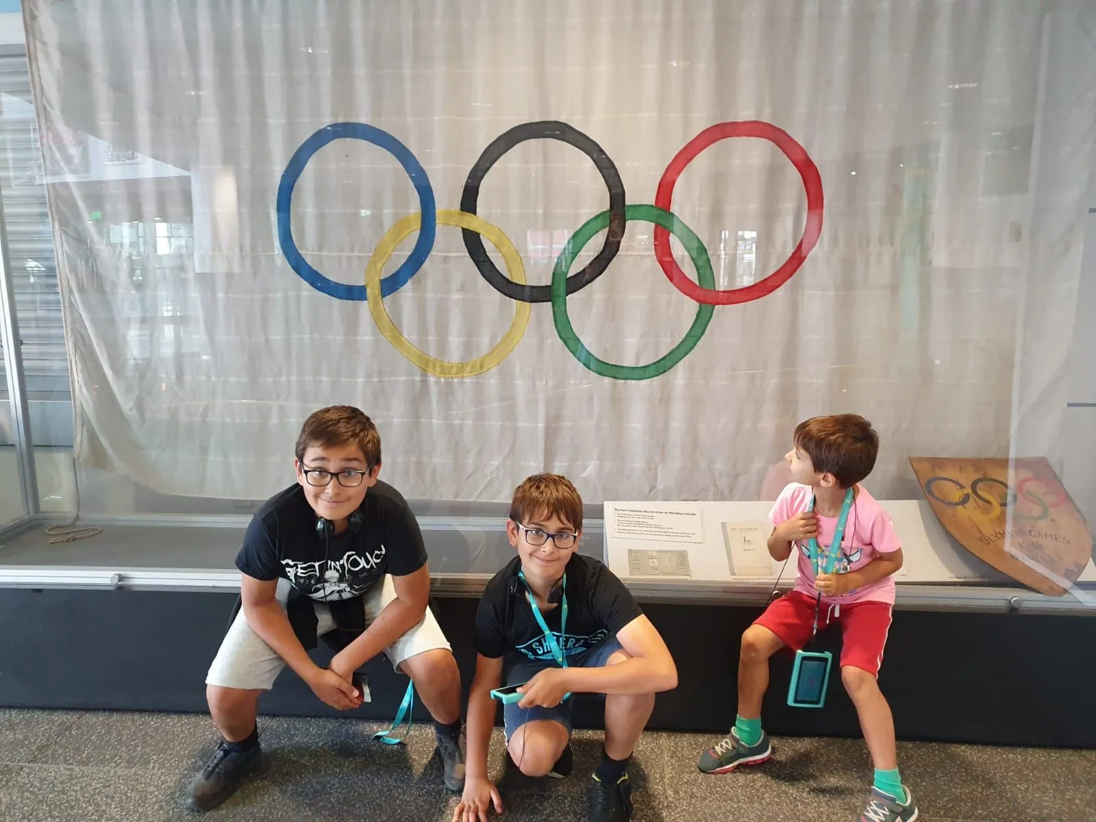 Three kids sat near the Olympics flag at Wembley Stadium