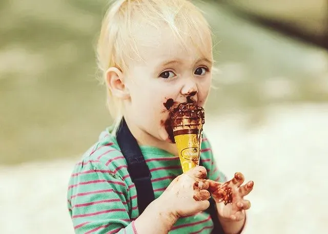 young blonde boy eating messy chocolate ice cream