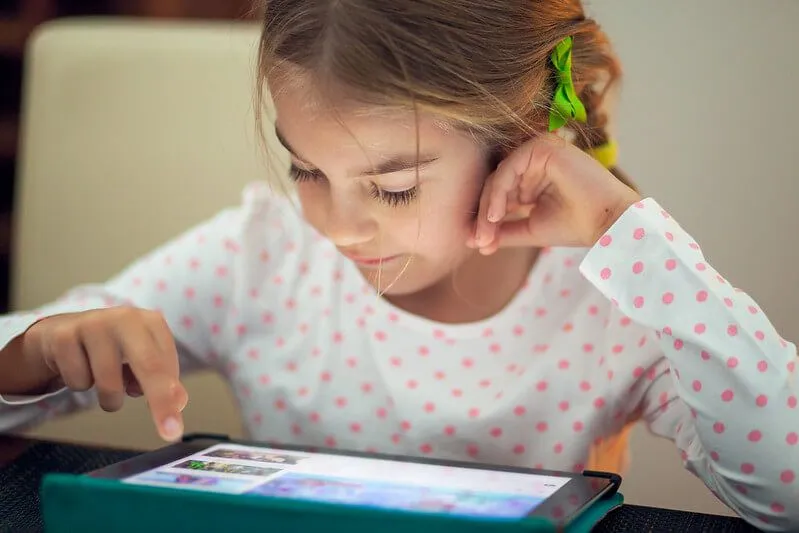 A young girl using a tablet to learn at home.