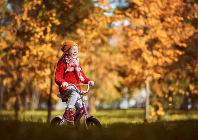 Young girl riding her bike in the park in Autumn