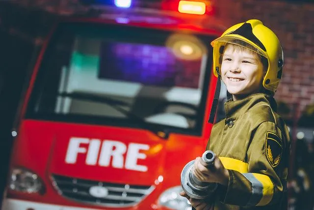 boy dressed up as a firefighter in front of fire engine
