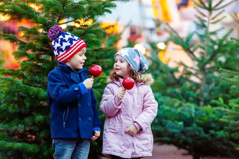 Kids eating apples outside in their hats and coats.