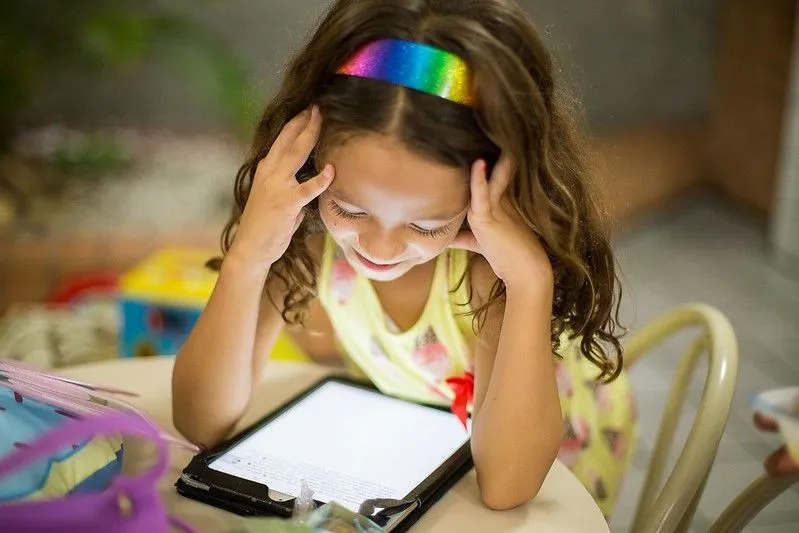 Girl with rainbow headband looking at unicorn jokes