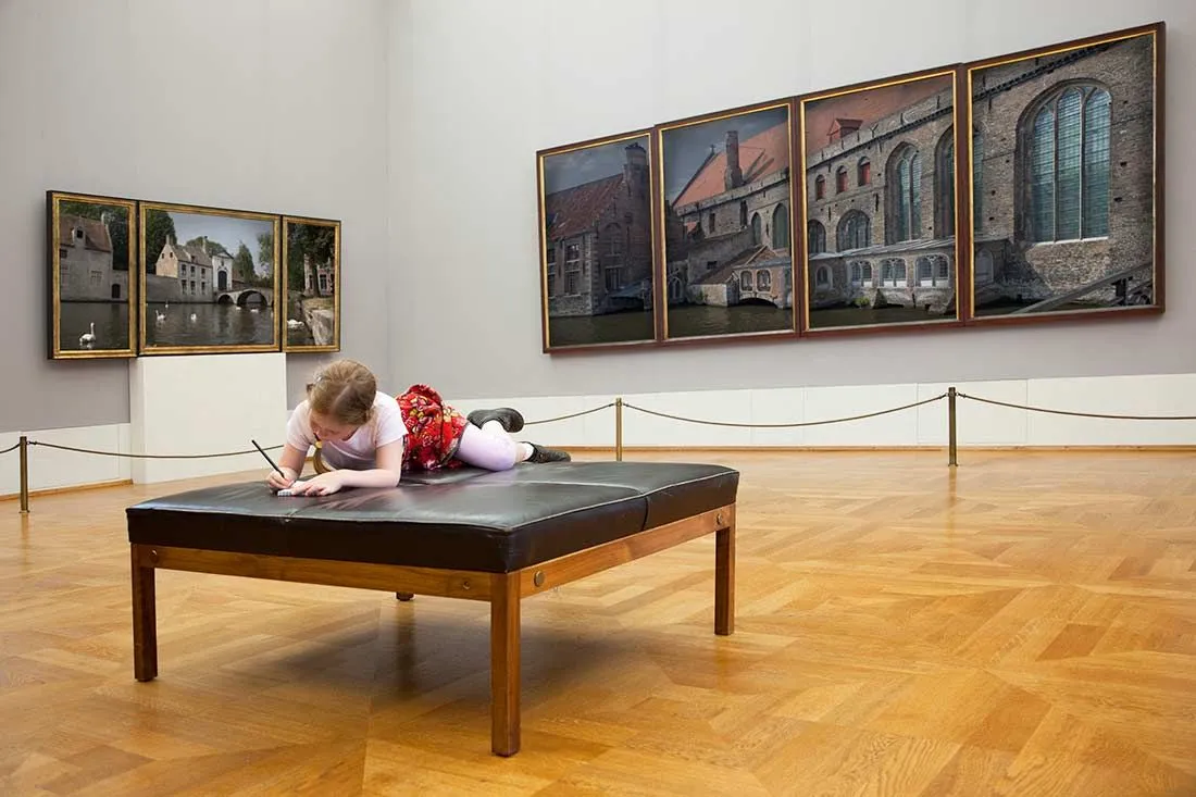 Child doing activity on a bench at an art gallery.