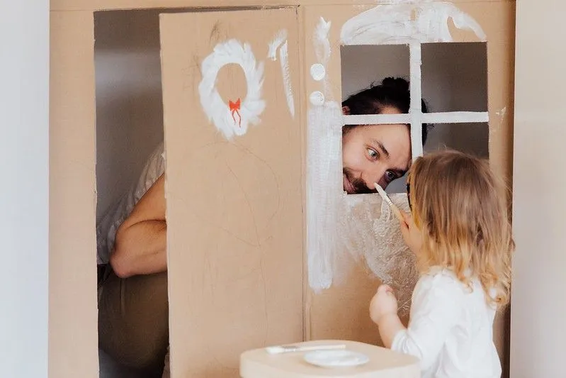 Playing in a DIY cardboard house at home.
