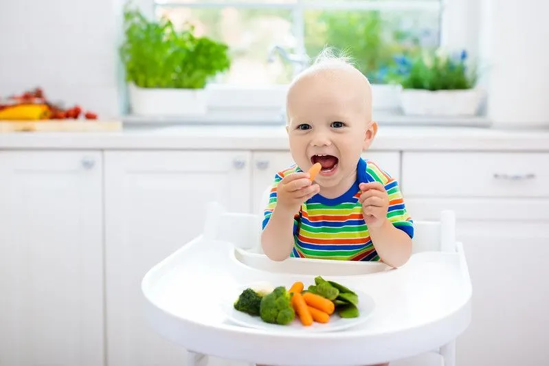Cute baby boy eating vegetables.