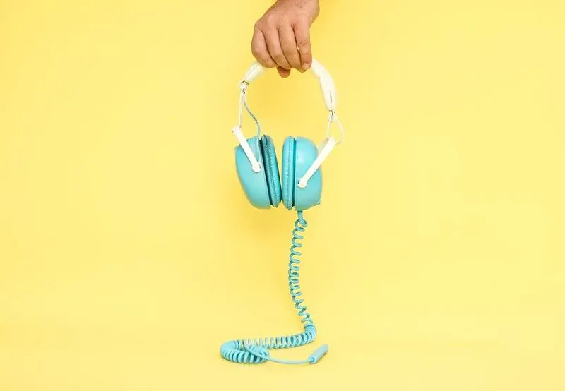 A pair of blue headphones against a yellow background.