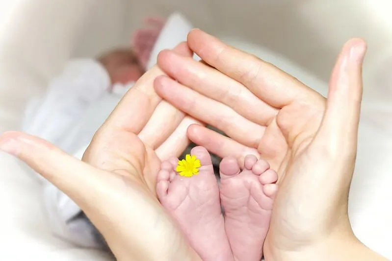 Mother holding her baby's feet with a tiny flower in it