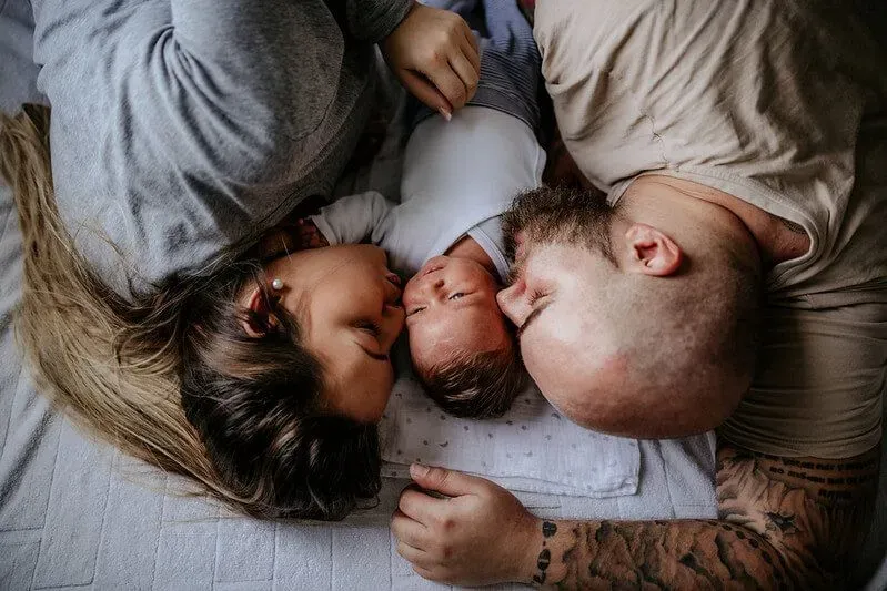 Mother and father cuddling up with their baby.