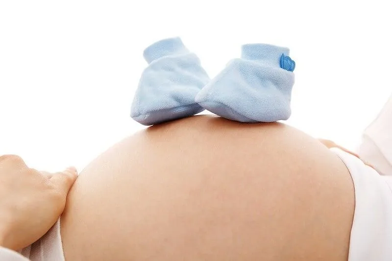Blue baby shoes on an expectant mother's pregnant belly