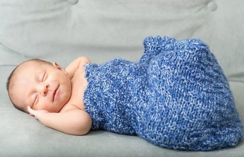 A newborn baby boy sleeping in blue swaddle
