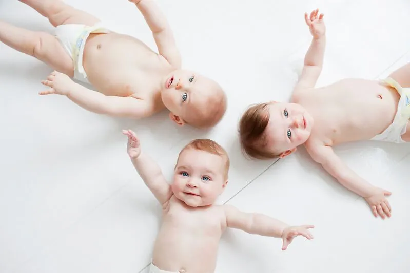 Three smiling babies on their back, whose boys names are beginning with Y.