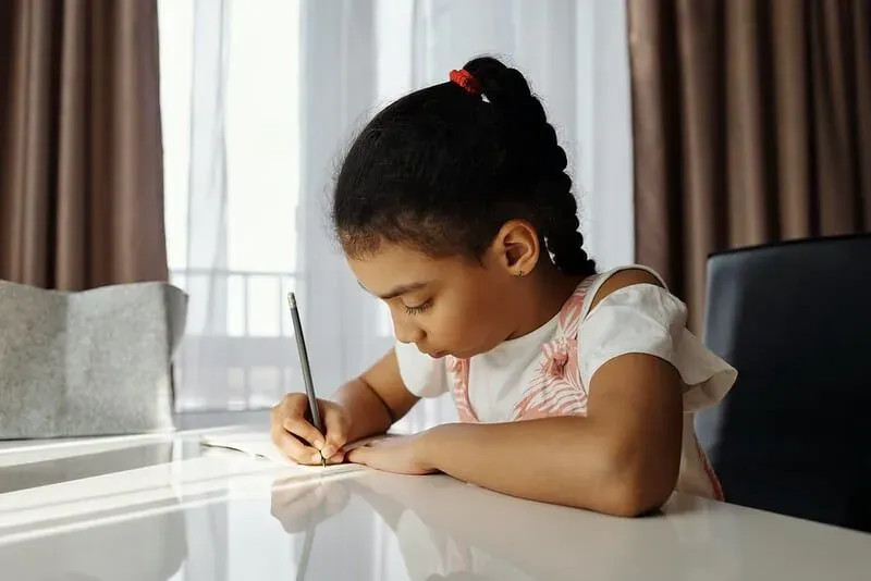 Little girl writing in notebook, trying to practice long division