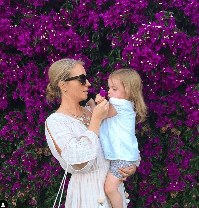 Robin Marsden and her daughter in front of a wall of flowers.