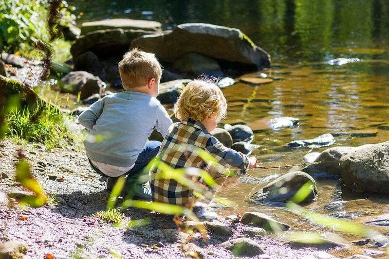 Children playing on the riverbank playing with rocks and telling rock puns