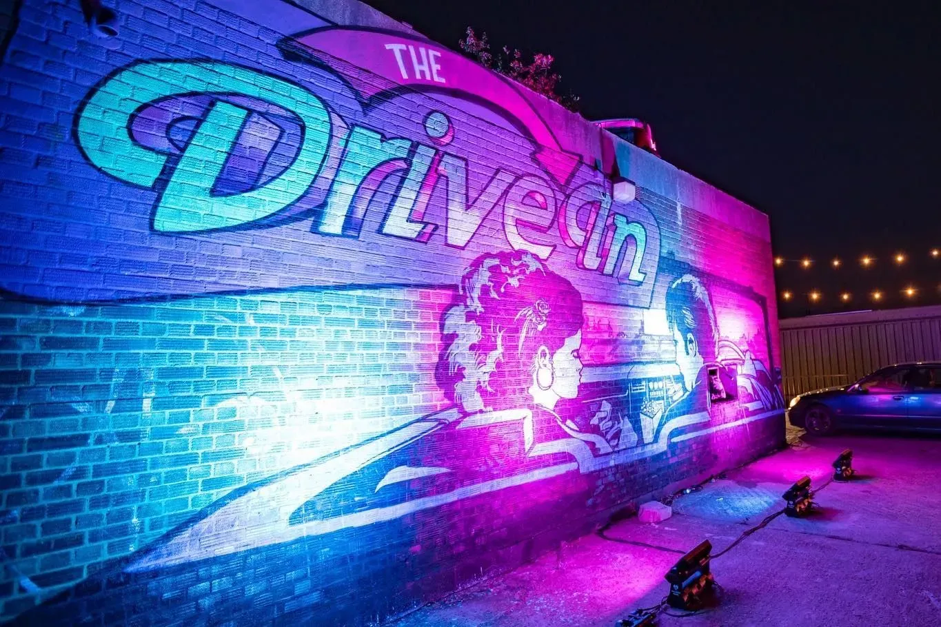 The Drive In logo projected against a wall in blue and purple.