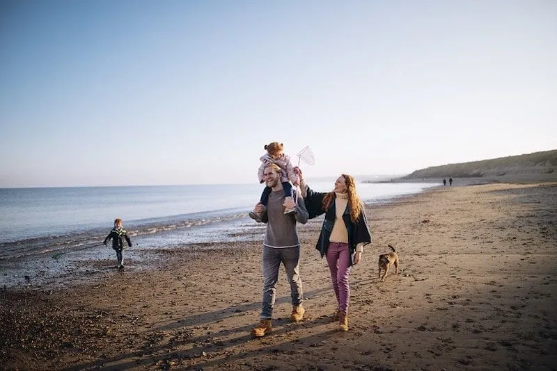 Family smiling, walking across the beach.