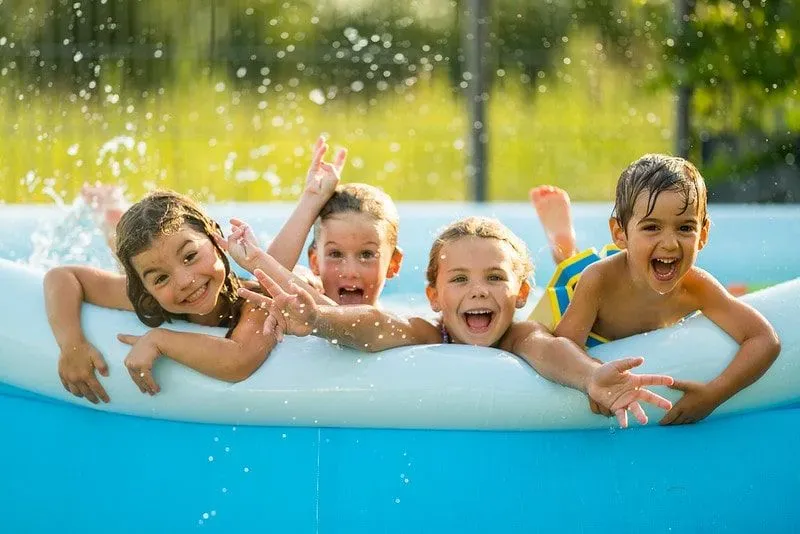 Four children in a paddling pool that's clean laughing, smiling, and enjoying themselves.