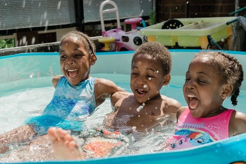 Three kids laughing and enjoying themselves in the clean paddling pool