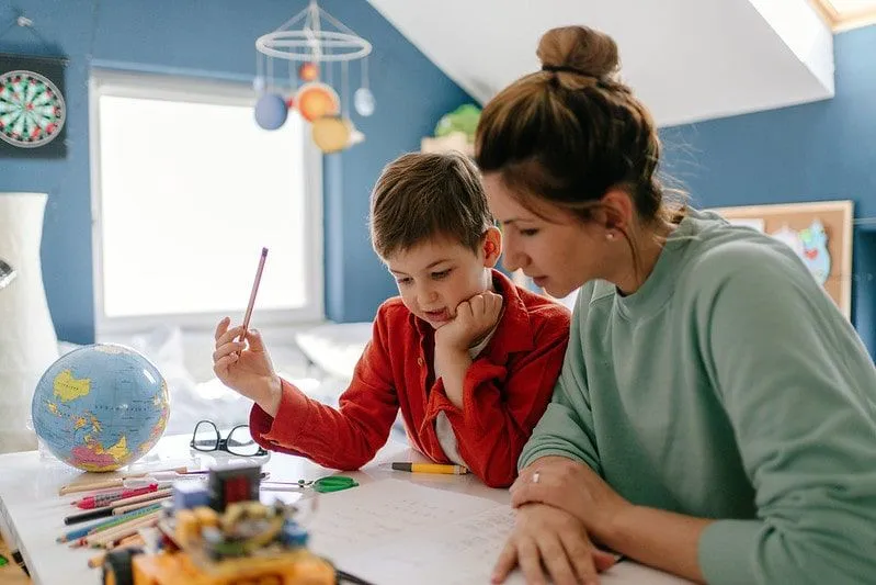 Mother sat with her son in his bedroom helping him learn multi-clause sentences.