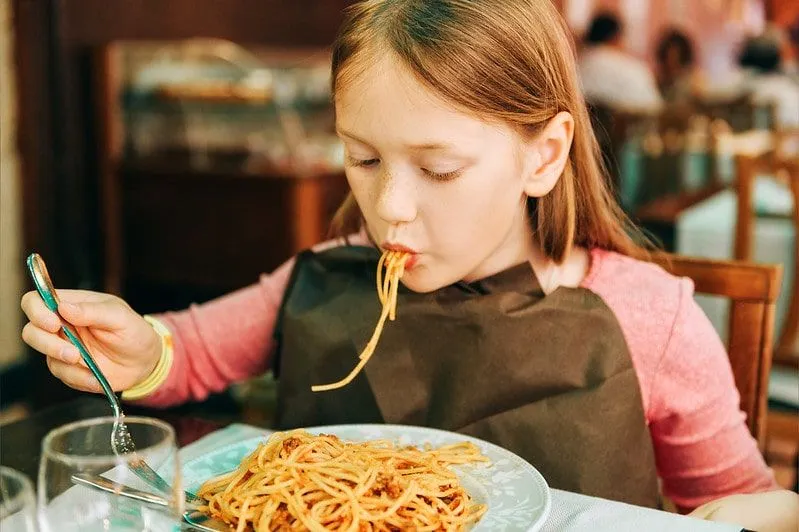 Girl eating spaghetti at a restaurant.